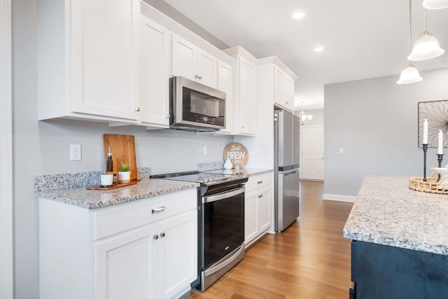 kitchen with decorative light fixtures, recessed lighting, appliances with stainless steel finishes, light wood-style floors, and white cabinets
