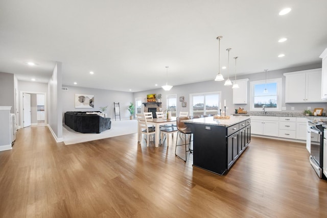 kitchen featuring stainless steel electric range oven, white cabinets, and light wood-style floors