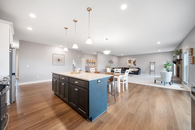 kitchen with recessed lighting, a kitchen breakfast bar, a kitchen island, and light wood-style floors