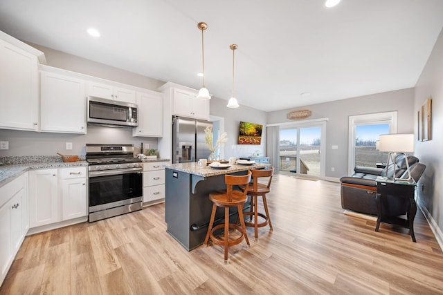 kitchen with light wood finished floors, a center island, open floor plan, appliances with stainless steel finishes, and white cabinets