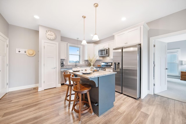 kitchen featuring a center island, white cabinets, stainless steel appliances, and a sink