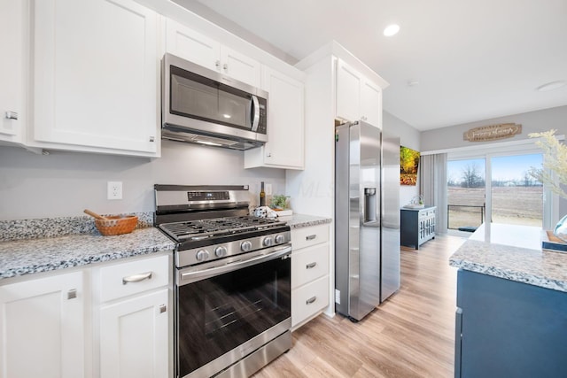 kitchen featuring white cabinets, light stone counters, light wood-type flooring, and stainless steel appliances