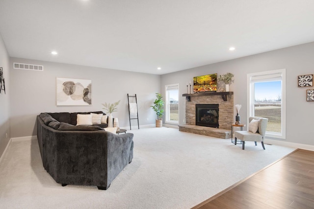 living room featuring recessed lighting, visible vents, plenty of natural light, and a stone fireplace