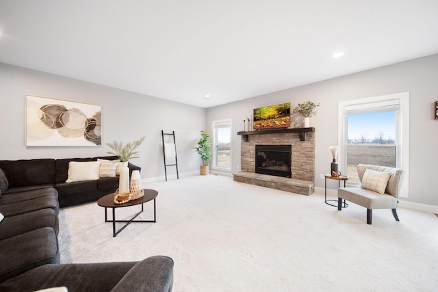 living area with recessed lighting, baseboards, a stone fireplace, and carpet flooring