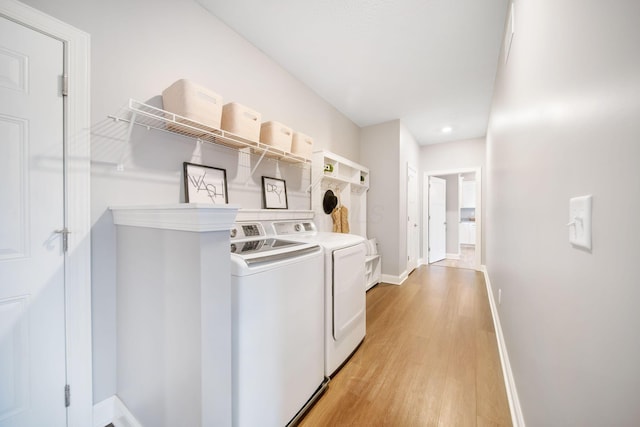 clothes washing area with laundry area, independent washer and dryer, light wood-style flooring, and baseboards