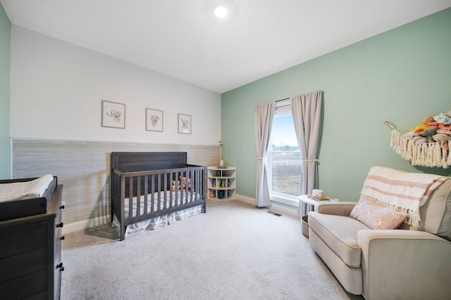 carpeted bedroom with baseboards and a nursery area