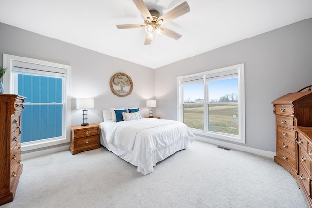bedroom featuring visible vents, baseboards, light colored carpet, and a ceiling fan