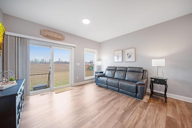 living area with light wood-style flooring, visible vents, and baseboards