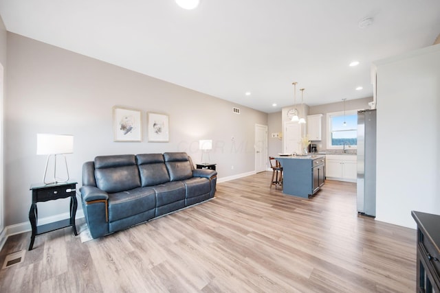living area with light wood finished floors, visible vents, recessed lighting, and baseboards