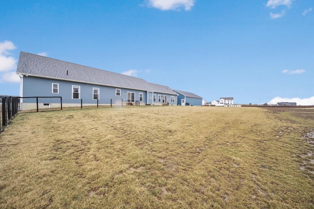 rear view of property featuring a yard and fence