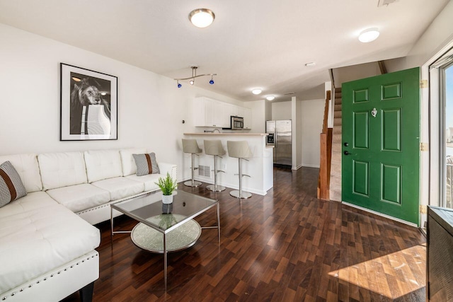 living area with visible vents, baseboards, and dark wood-style floors