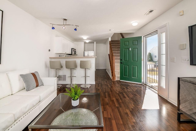 living area with visible vents, stairs, dark wood-type flooring, and baseboards