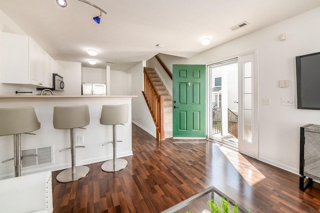 kitchen with white cabinetry, refrigerator, visible vents, and dark wood-style flooring