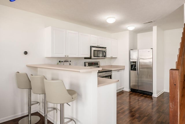 kitchen with visible vents, a breakfast bar area, light countertops, appliances with stainless steel finishes, and dark wood-style flooring