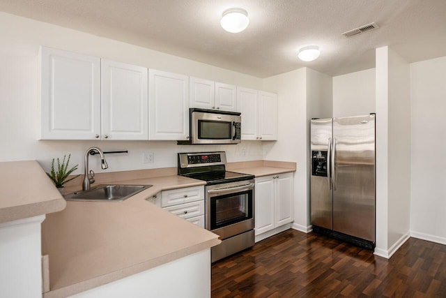 kitchen featuring visible vents, dark wood finished floors, a sink, appliances with stainless steel finishes, and white cabinetry