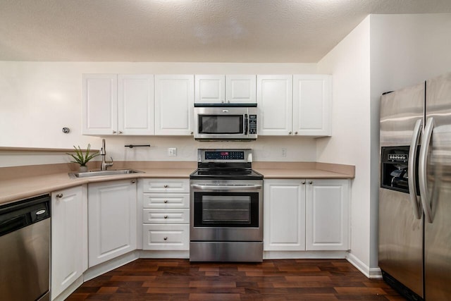 kitchen with dark wood finished floors, white cabinets, stainless steel appliances, and a sink