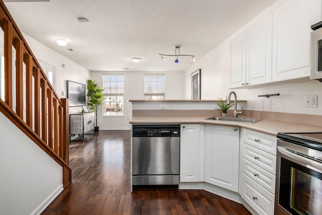 kitchen with a sink, dark wood finished floors, appliances with stainless steel finishes, a peninsula, and light countertops