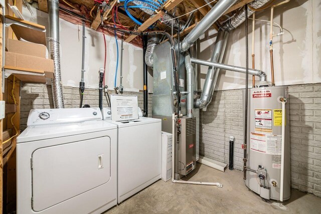 laundry area with laundry area, washing machine and dryer, water heater, and brick wall