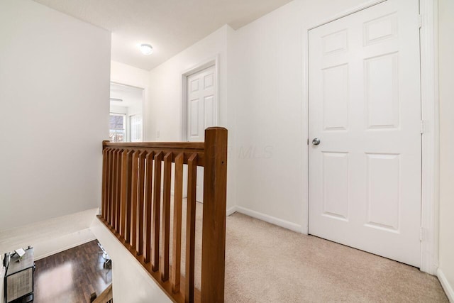 hall with baseboards, an upstairs landing, and carpet