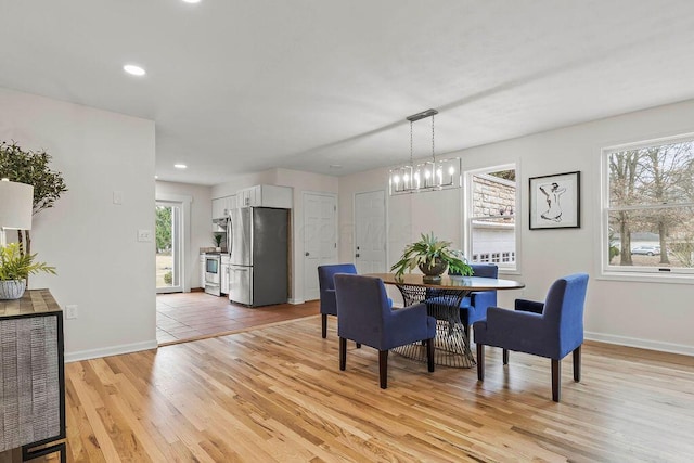 dining area with recessed lighting, baseboards, light wood finished floors, and an inviting chandelier