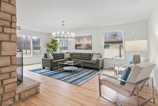 living area with a wealth of natural light, a notable chandelier, baseboards, and wood finished floors