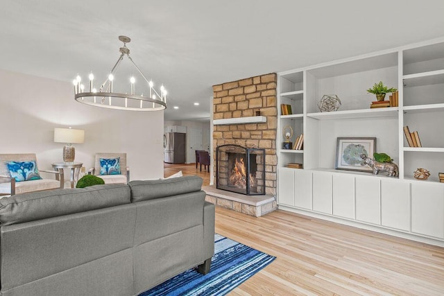 living room featuring a chandelier, a fireplace, built in shelves, and wood finished floors