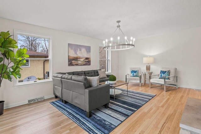 living area featuring a chandelier, wood finished floors, visible vents, and baseboards