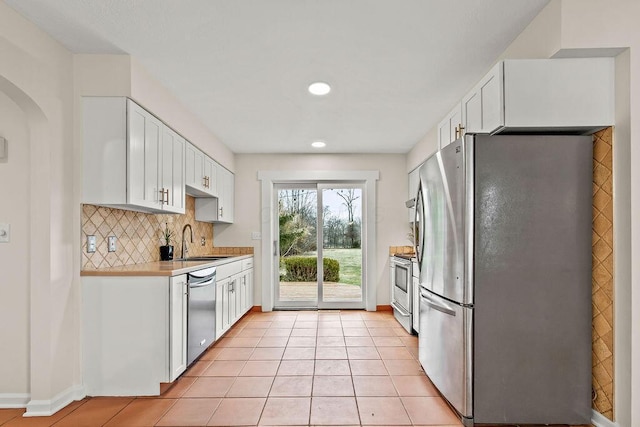 kitchen featuring tasteful backsplash, appliances with stainless steel finishes, light countertops, white cabinetry, and a sink