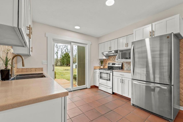 kitchen with stainless steel appliances, tasteful backsplash, light countertops, a sink, and under cabinet range hood