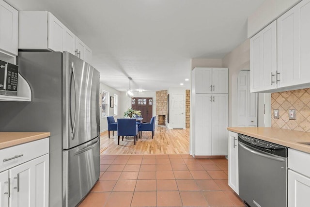 kitchen with light tile patterned floors, stainless steel appliances, white cabinets, and decorative backsplash