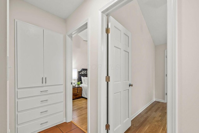 corridor featuring light wood-style flooring and baseboards