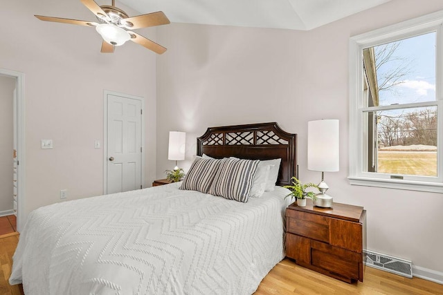 bedroom with light wood-type flooring, visible vents, lofted ceiling, and multiple windows