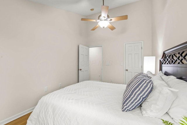 bedroom with a ceiling fan, a towering ceiling, baseboards, and wood finished floors