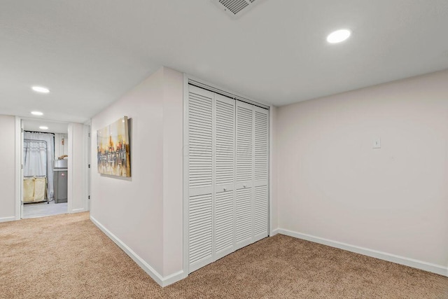 hallway with carpet floors, visible vents, and baseboards