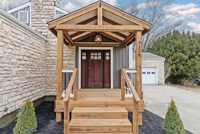 entrance to property featuring a garage, stone siding, board and batten siding, and concrete driveway