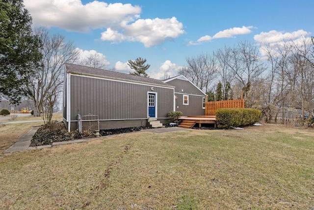 back of house featuring entry steps, a wooden deck, and a yard