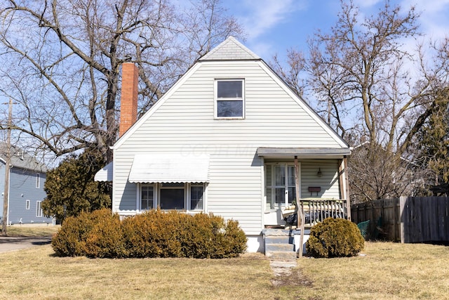 view of front of home with a porch, a front yard, and fence