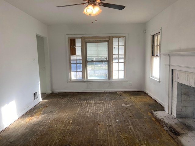 unfurnished living room with a fireplace, visible vents, a ceiling fan, baseboards, and hardwood / wood-style floors