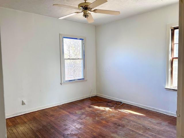 spare room with a wealth of natural light, wood-type flooring, and baseboards