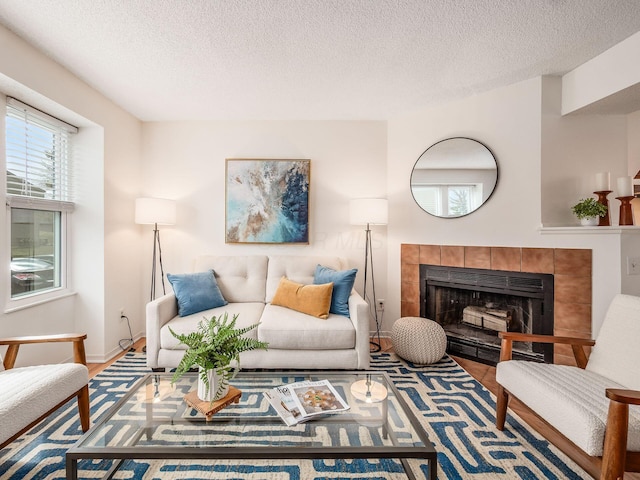 living area featuring a fireplace, a textured ceiling, and baseboards