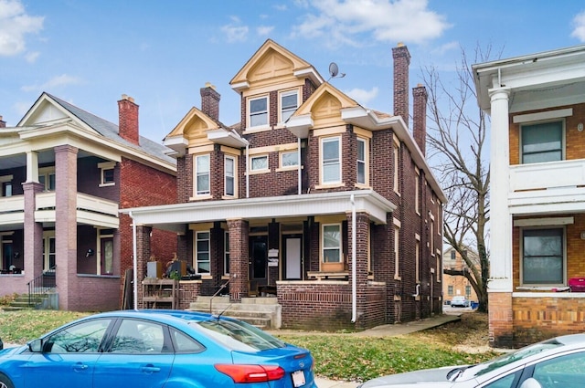 view of front of property featuring brick siding, a chimney, and a porch