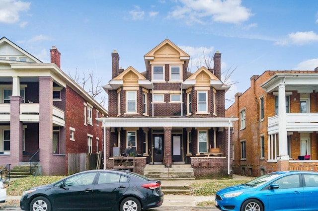 multi unit property featuring a porch and brick siding