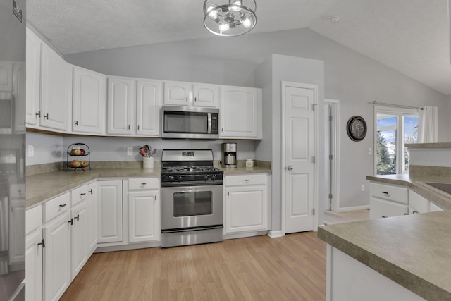 kitchen featuring stainless steel appliances, lofted ceiling, light wood-type flooring, and white cabinets