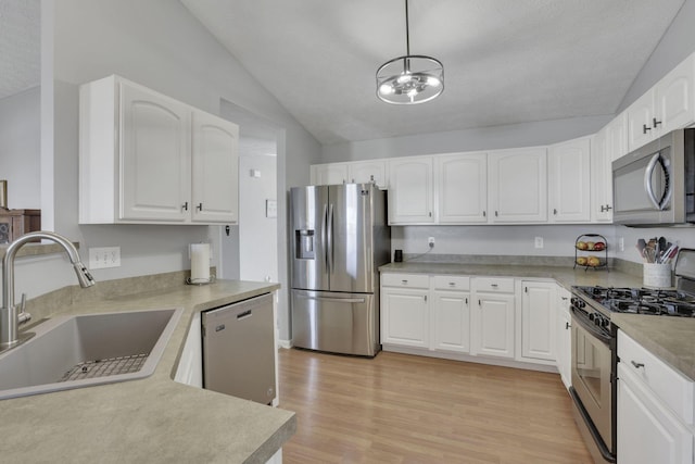 kitchen featuring stainless steel appliances, a sink, white cabinetry, vaulted ceiling, and light wood-type flooring