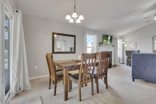 dining space featuring lofted ceiling, a chandelier, light colored carpet, a fireplace with flush hearth, and baseboards