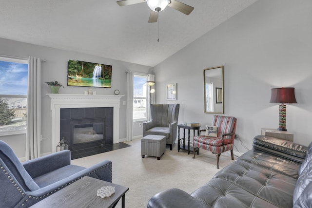 living room with a tile fireplace, lofted ceiling, ceiling fan, a textured ceiling, and carpet floors