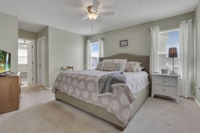 bedroom featuring light carpet, multiple windows, and a textured ceiling