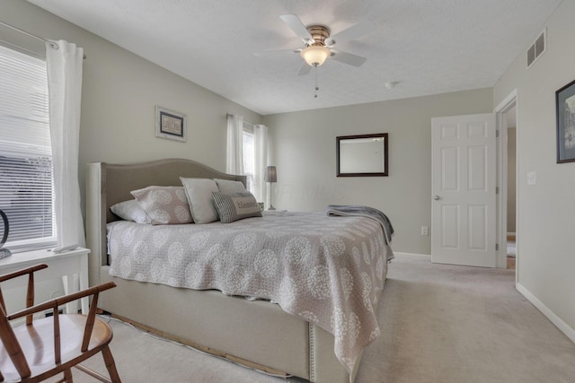 bedroom featuring ceiling fan, a textured ceiling, light carpet, visible vents, and baseboards