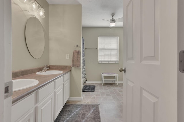 full bath featuring a sink, a textured ceiling, baseboards, and double vanity