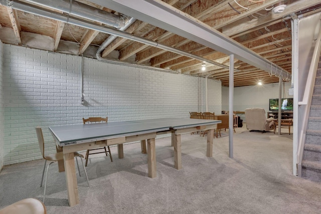 recreation room with carpet and brick wall